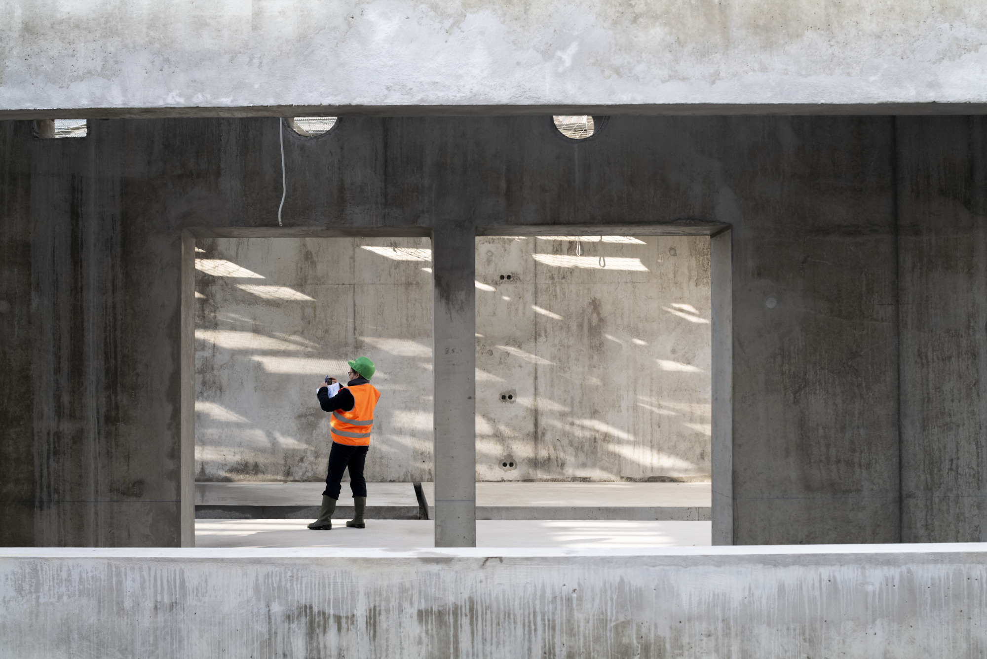 Journaliste photographiant l'ossature en béton brut du Prisme depuis une baie, projet de Christophe Gulizzi architecte à Bobigny