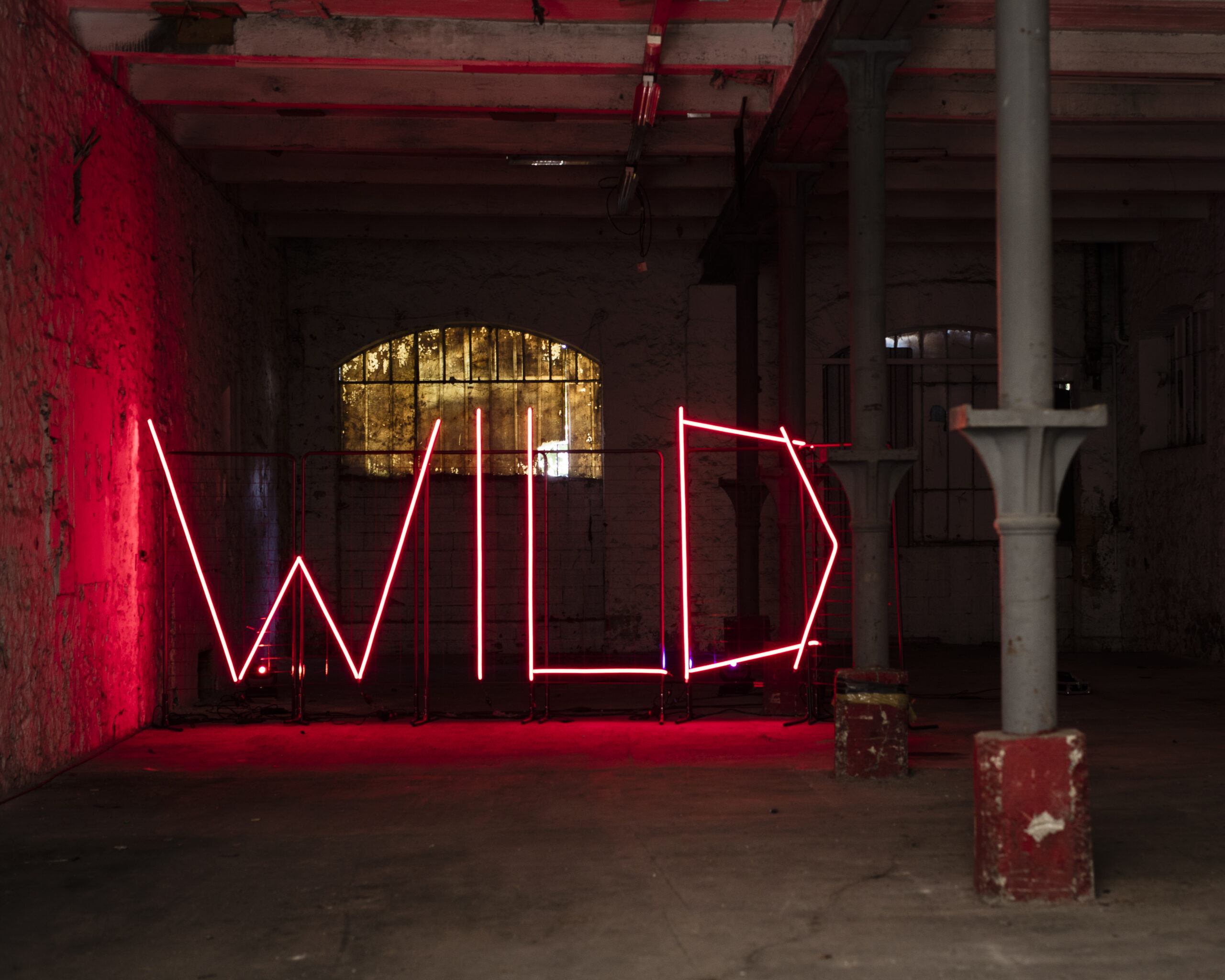 Enseigne néon rouge WILD à l'entrée de la friche industrielle accueillant le Festival de la Ville Sauvage à Marseille
