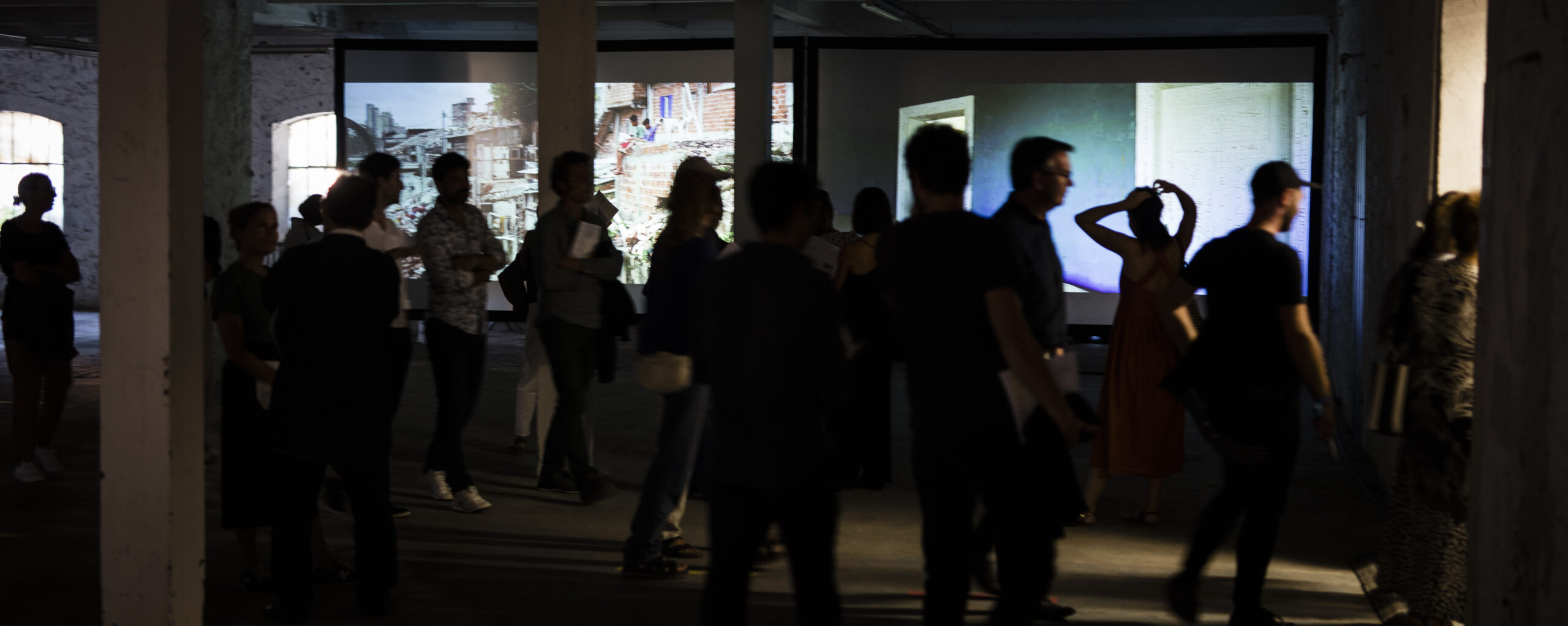 Visiteurs en silhouette devant des projections vidéo sur l'architecture urbaine, lors du Festival de la Ville Sauvage à Marseille